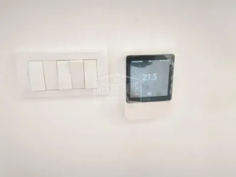Prekidači za svetlo i digitalni termostat na belom zidu. - image 2