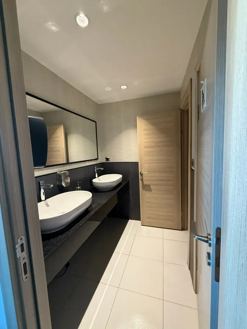 Modern restroom with two washbasins and a mirror.