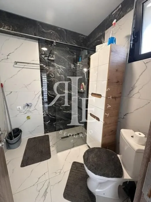 Modern bathroom with a walk-in shower and white marble-patterned ceramic tiles.