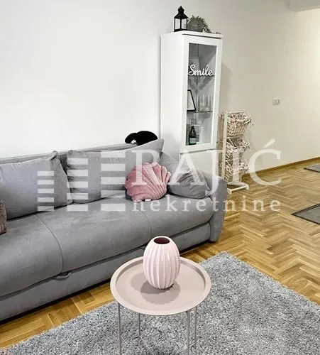 Living room with a grey sofa and parquet flooring.