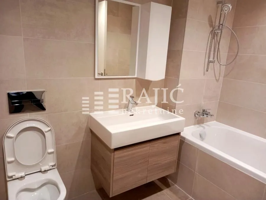 Modernly equipped bathroom with a bathtub, washbasin, and toilet.