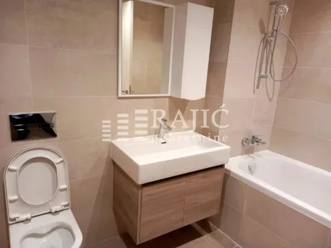 Modernly equipped bathroom with a bathtub, washbasin, and toilet. - image 9