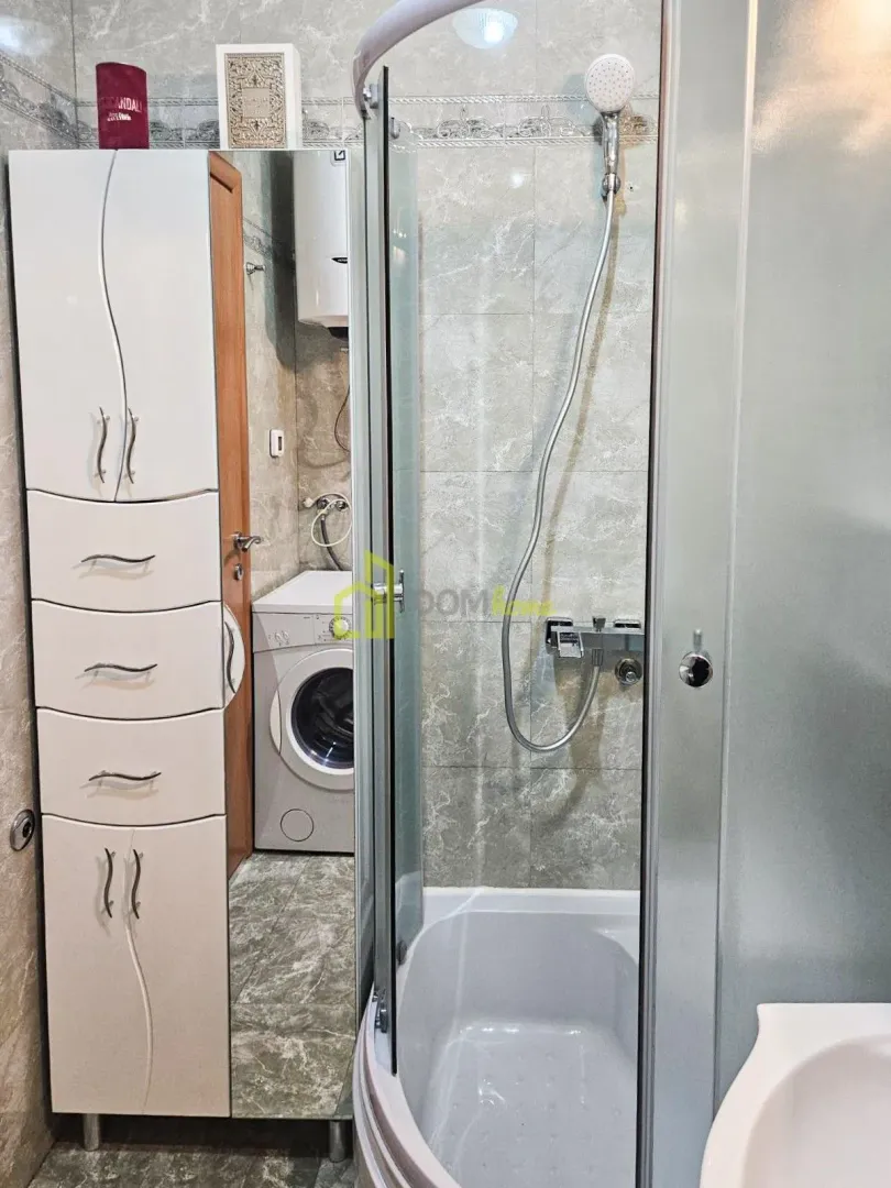 Bathroom with a shower cabin, a cabinet, and a washing machine.