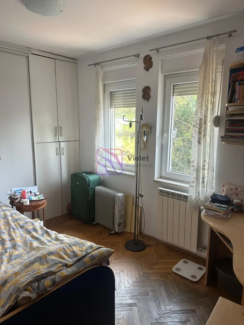 Manja spavaća soba sa krevetom, plakarom i radnim stolom.