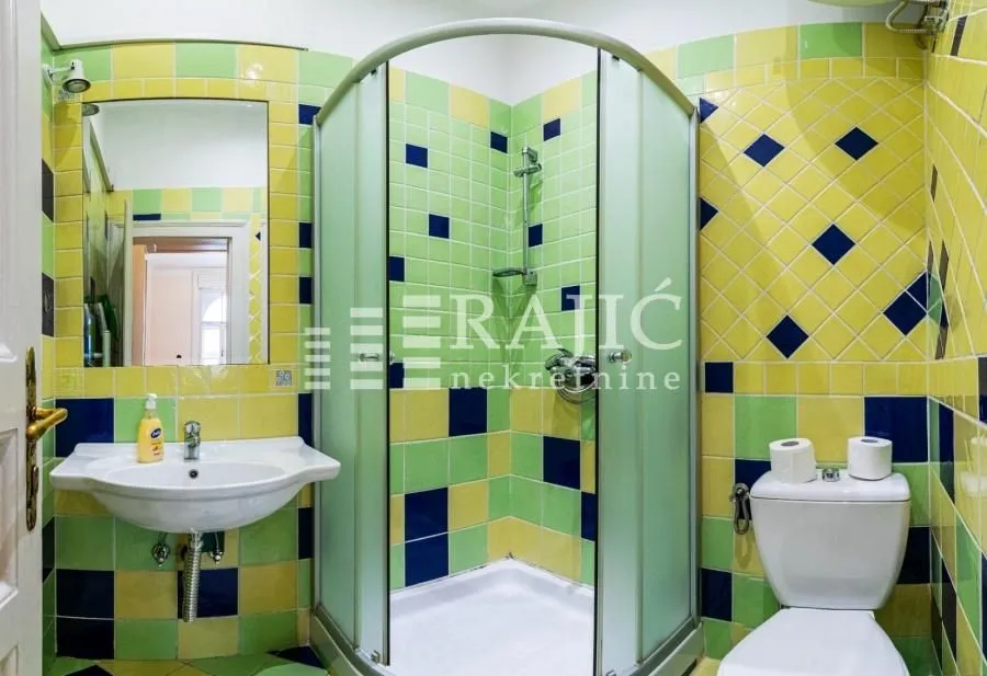 Bathroom with a shower cabin and colorful tiles.