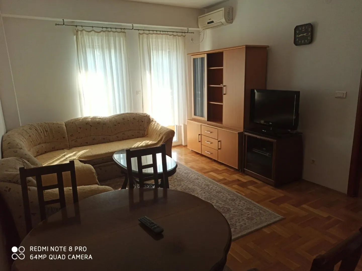 Dnevna soba sa ugaonom garniturom, drvenim namještajem i trpezarijskim stolom.