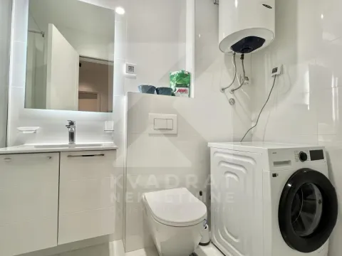 Modern bathroom with a washbasin, toilet, washing machine, and water heater. - image 3