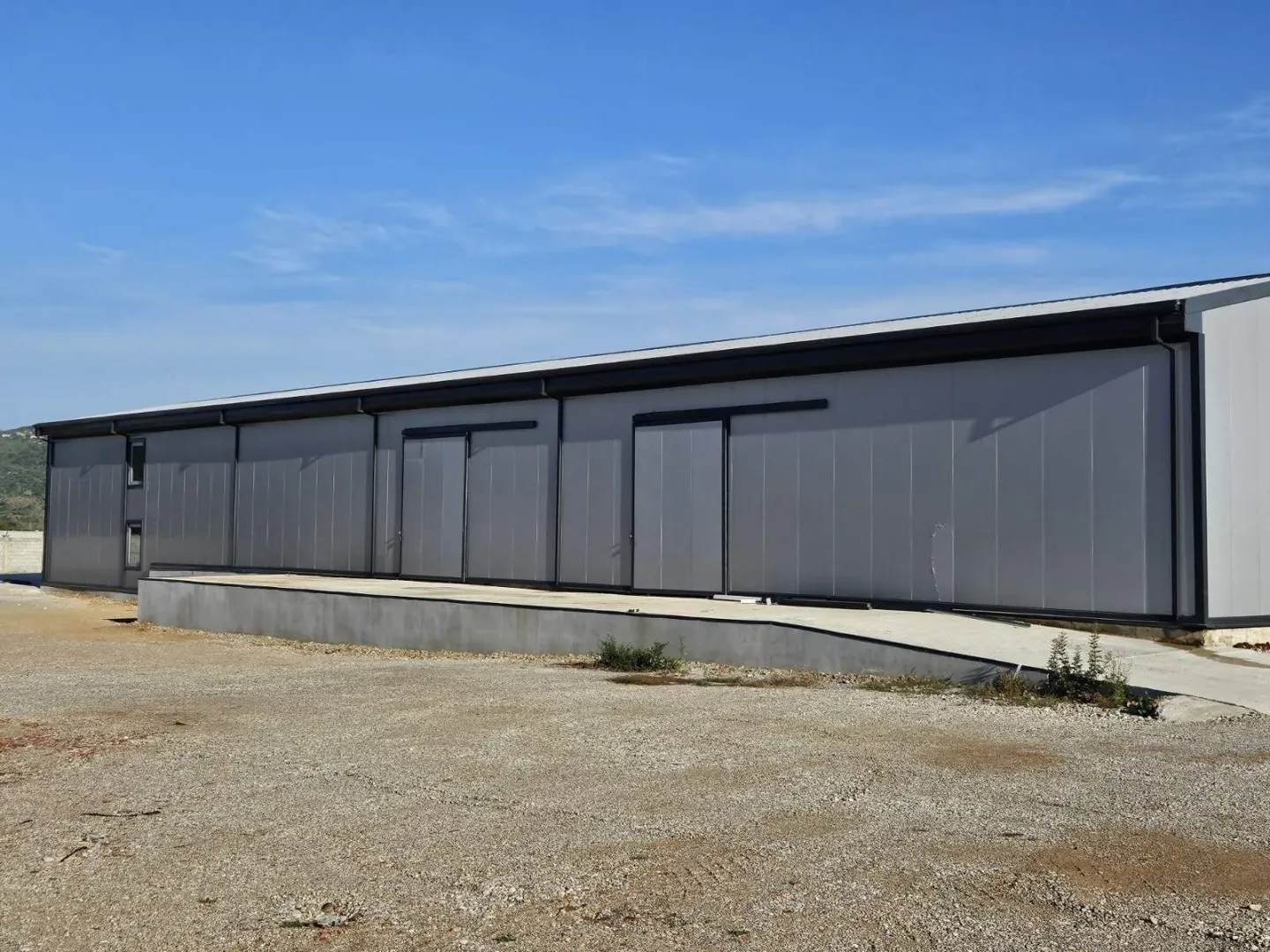 Exterior view of a modern industrial building or warehouse with a concrete ramp.