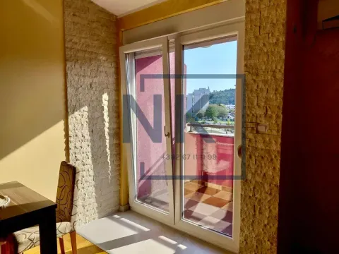 Pogled kroz balkonska vrata prema terasi sa dekorativnim kamenim zidovima u enterijeru. - image 6