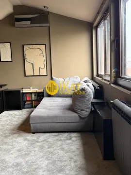 Living room with a gray sofa, carpet, and bookshelves next to the window. - image 9