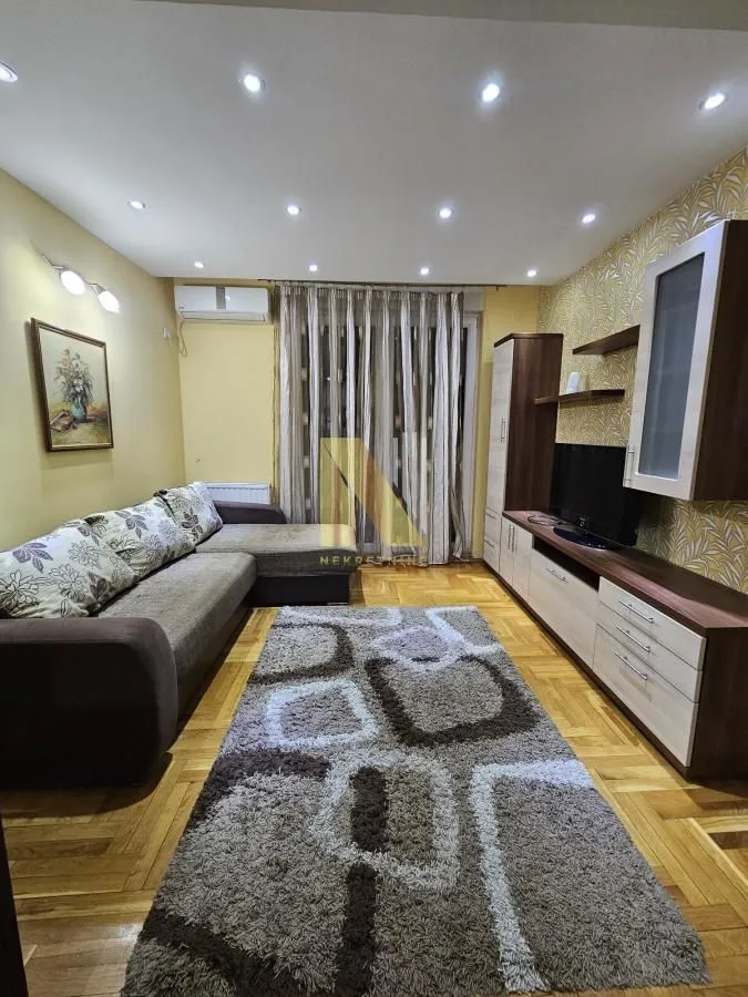 Dnevna soba sa garniturom za sedenje, TV komodom i parketom.