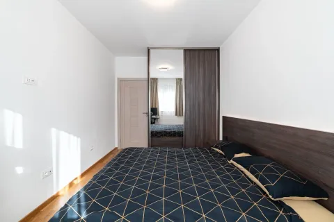 Svijetla spavaća soba sa bračnim krevetom, velikim ormarom i drvenim vratima. - image 9