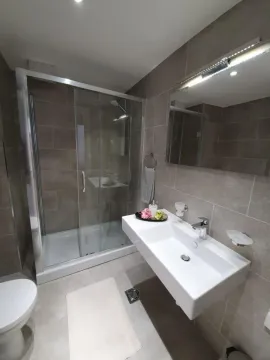 Modern bathroom equipped with a walk-in shower and washbasin. - image 3