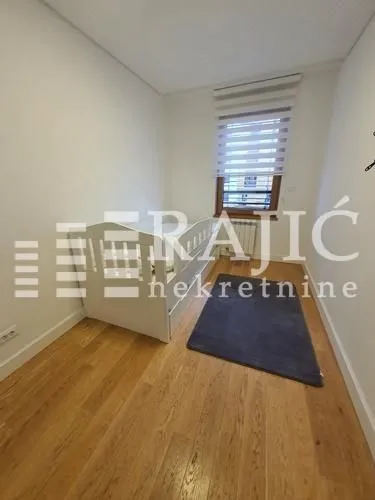 Children's bedroom with a bed, wooden flooring, and a window.