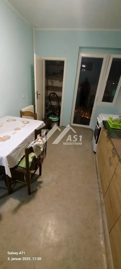 Kuhinja sa trpezarijskim stolom i izlazom na terasu.