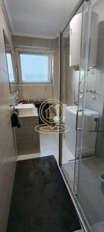 Kupatilo opremljeno tuš kabinom, umivaonikom, wc šoljom i bojlerom.