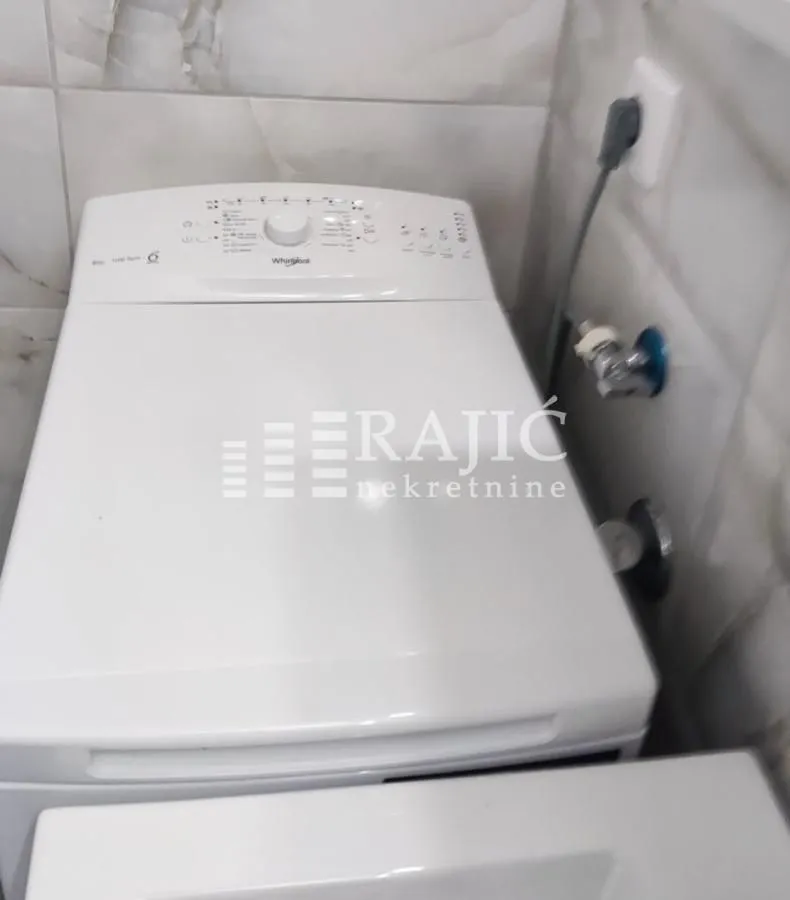 Bathroom with a washing machine and tiling.