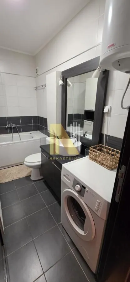 Kupatilo opremljeno kadom, umivaonikom, WC šoljom i veš mašinom.