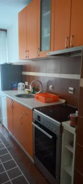 Functional kitchen featuring orange cabinets and a built-in stove. - image 4