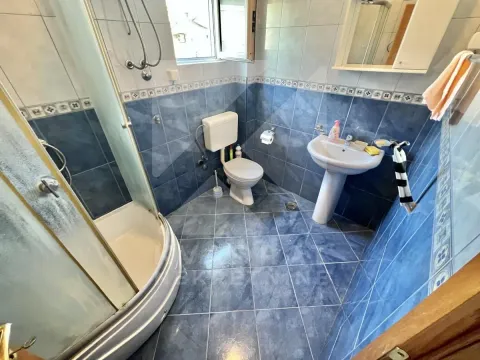 Tiled bathroom with a shower cabin, washbasin, and toilet. - image 3