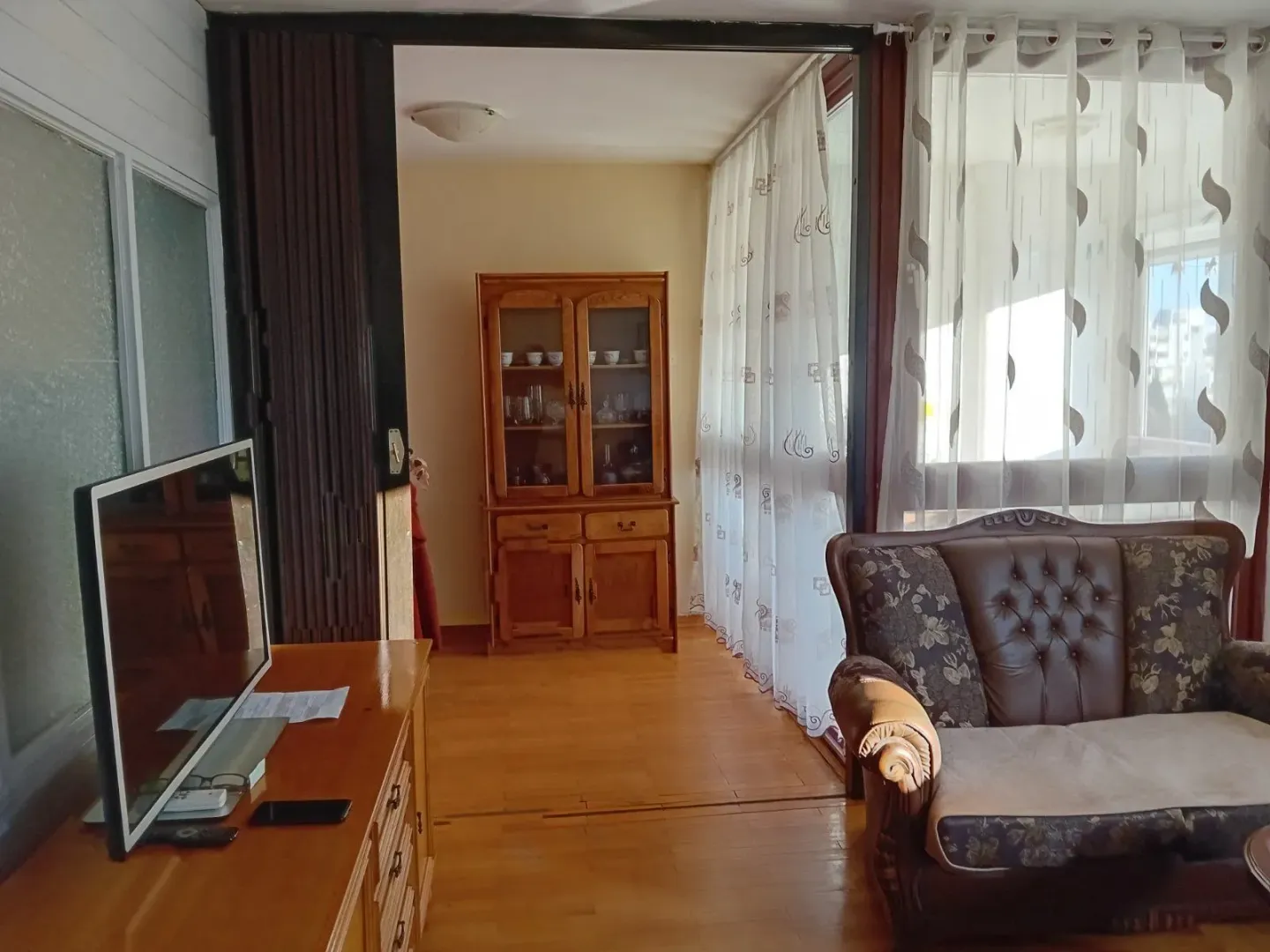 Svijetla dnevna soba sa klasičnim namještajem i drvenim podom.