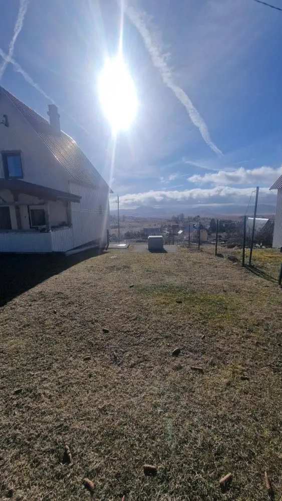 Prostrano dvorište pored kuće pod sunčanim nebom.