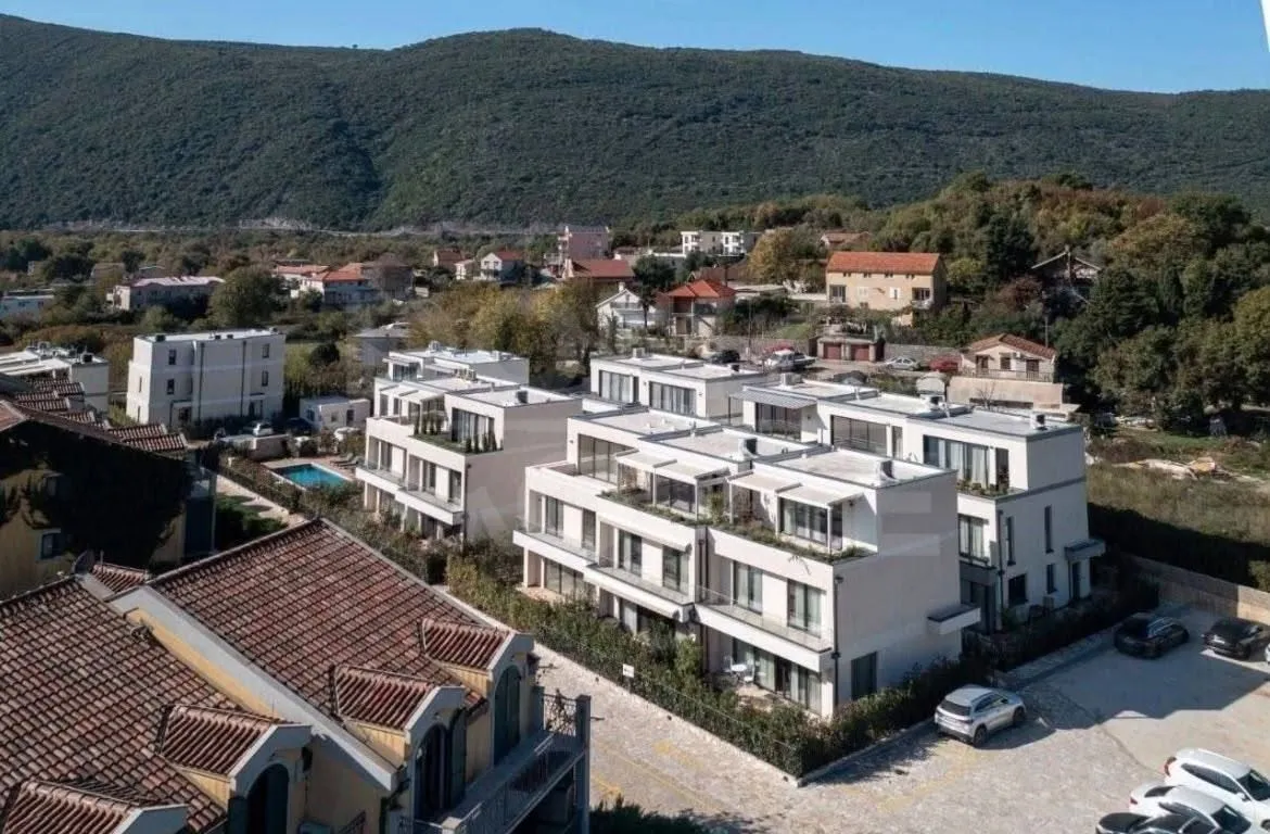 Aerial view of a residential complex with a swimming pool and surrounding greenery.