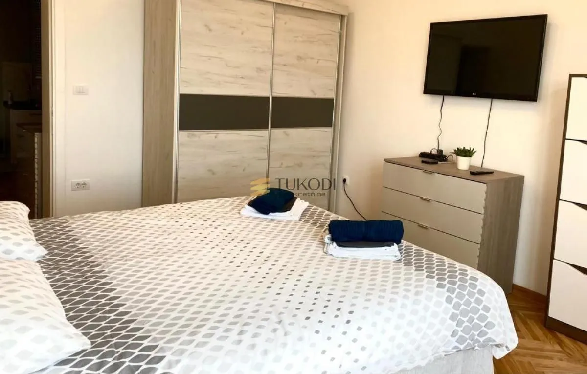 Furnished bedroom with a large double bed, wardrobe, and television.