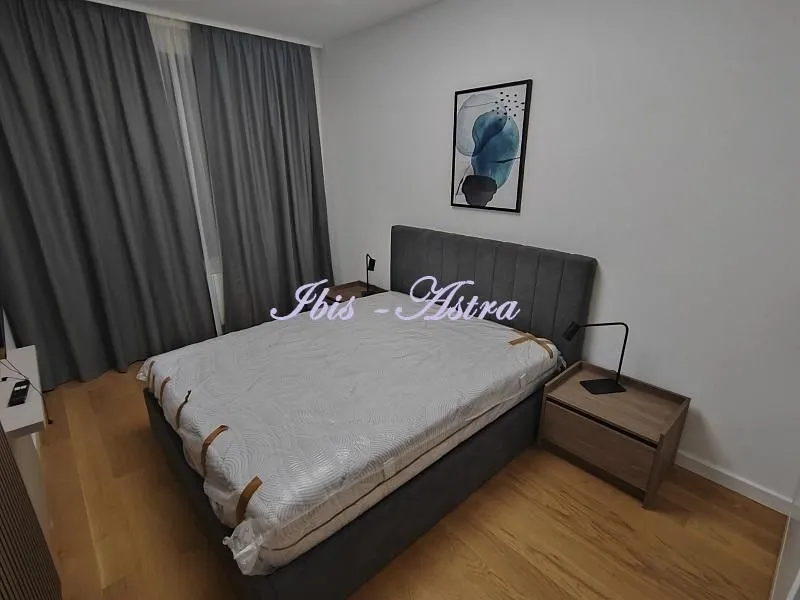 Furnished bedroom with a double bed, bedside table, and curtains.