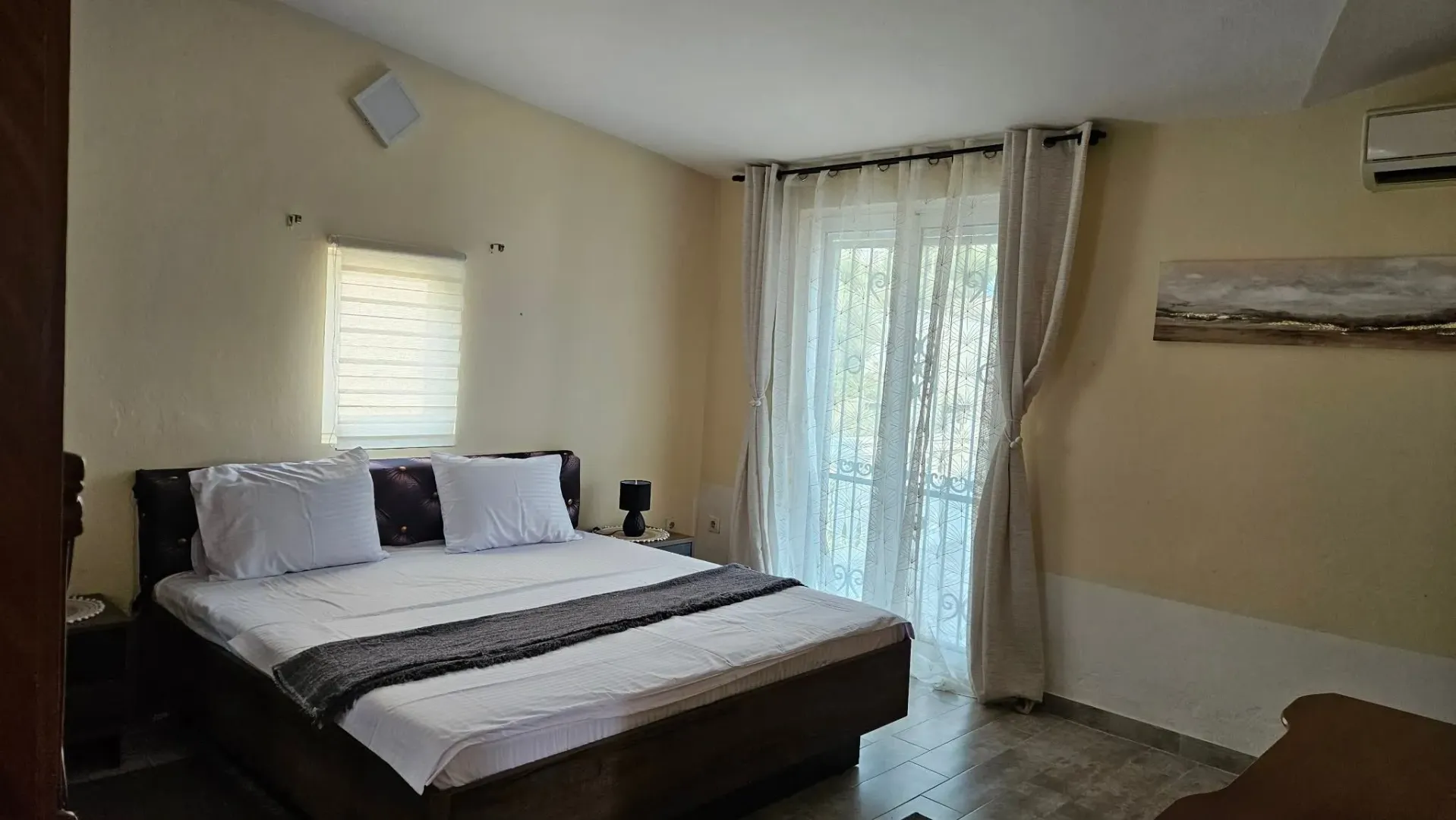 Bedroom with a double bed, window, and balcony doors.