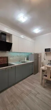 Moderna kuhinja sa bijelim i sivim elementima i trpezarijskim stolom. - image 7