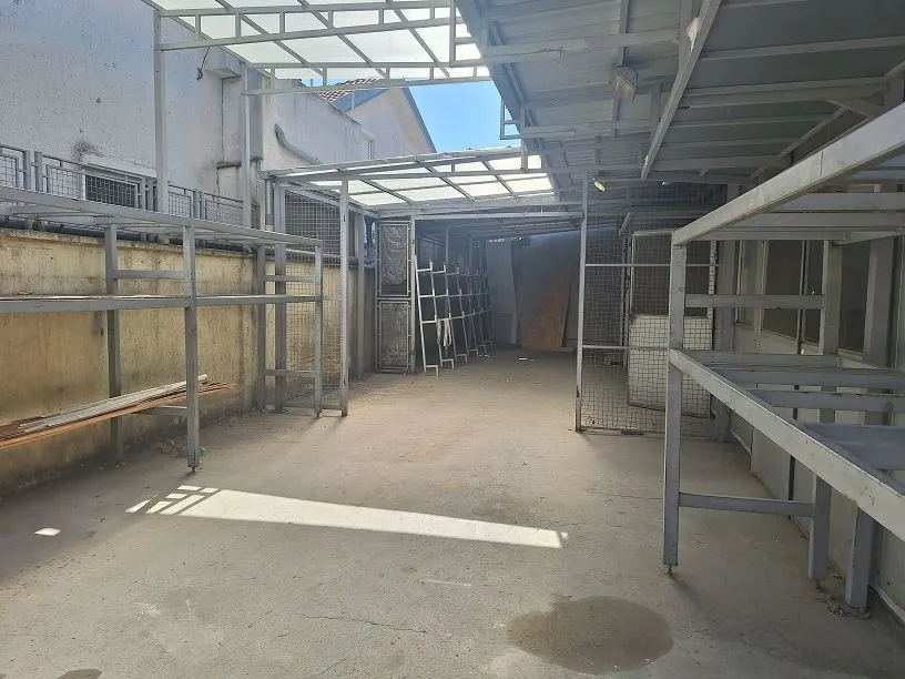 Covered outdoor area with metal structures and shelving in the yard.