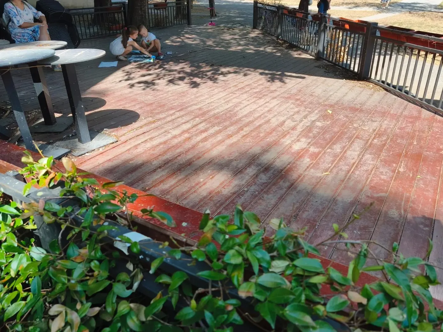 Wooden terrace with a fence and tables.