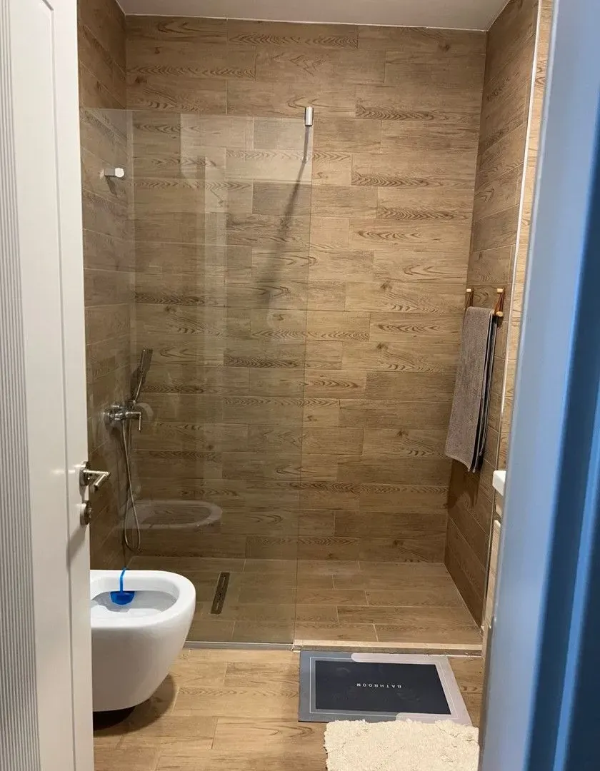 Modern bathroom with a walk-in shower and wood-effect wall tiles.