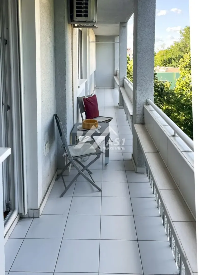 Dugačka natkrivena terasa sa stolom i stolicama.