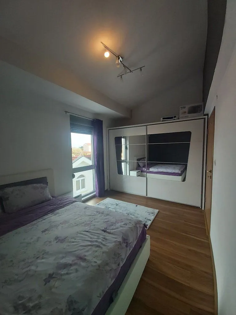 Spavaća soba sa bračnim krevetom, velikim ormarom i prozorom.