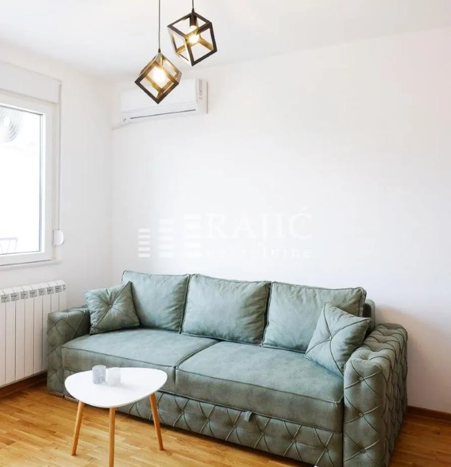 Living room with a green sofa and a modern chandelier.