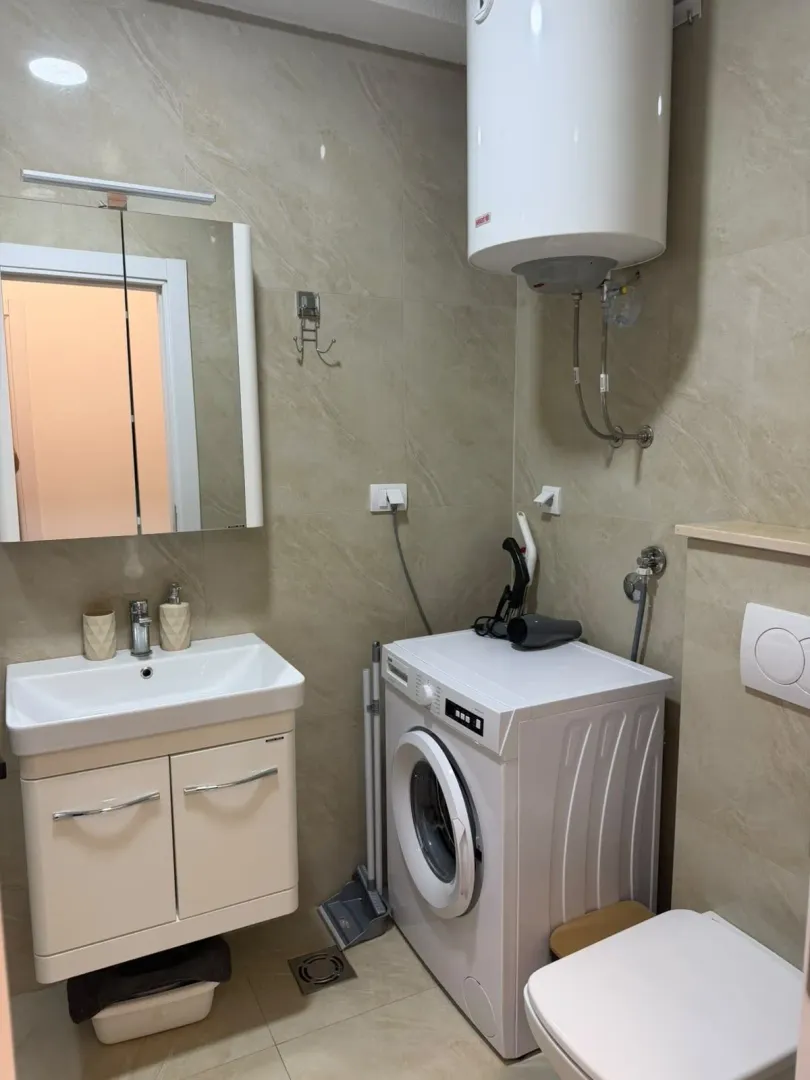 Small bathroom with a sink, washing machine, and water heater.