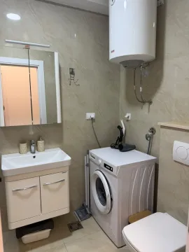 Small bathroom with a sink, washing machine, and water heater. - image 7