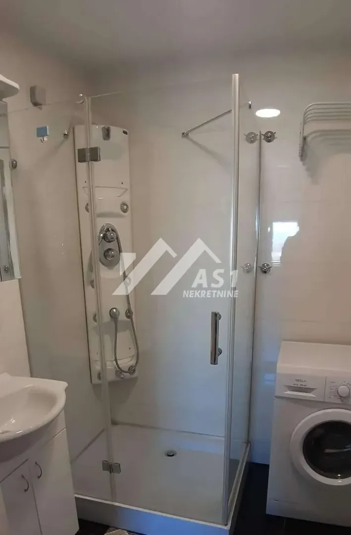 Bathroom with a shower cabin, washbasin, and washing machine.