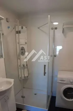Bathroom with a shower cabin, washbasin, and washing machine. - image 5