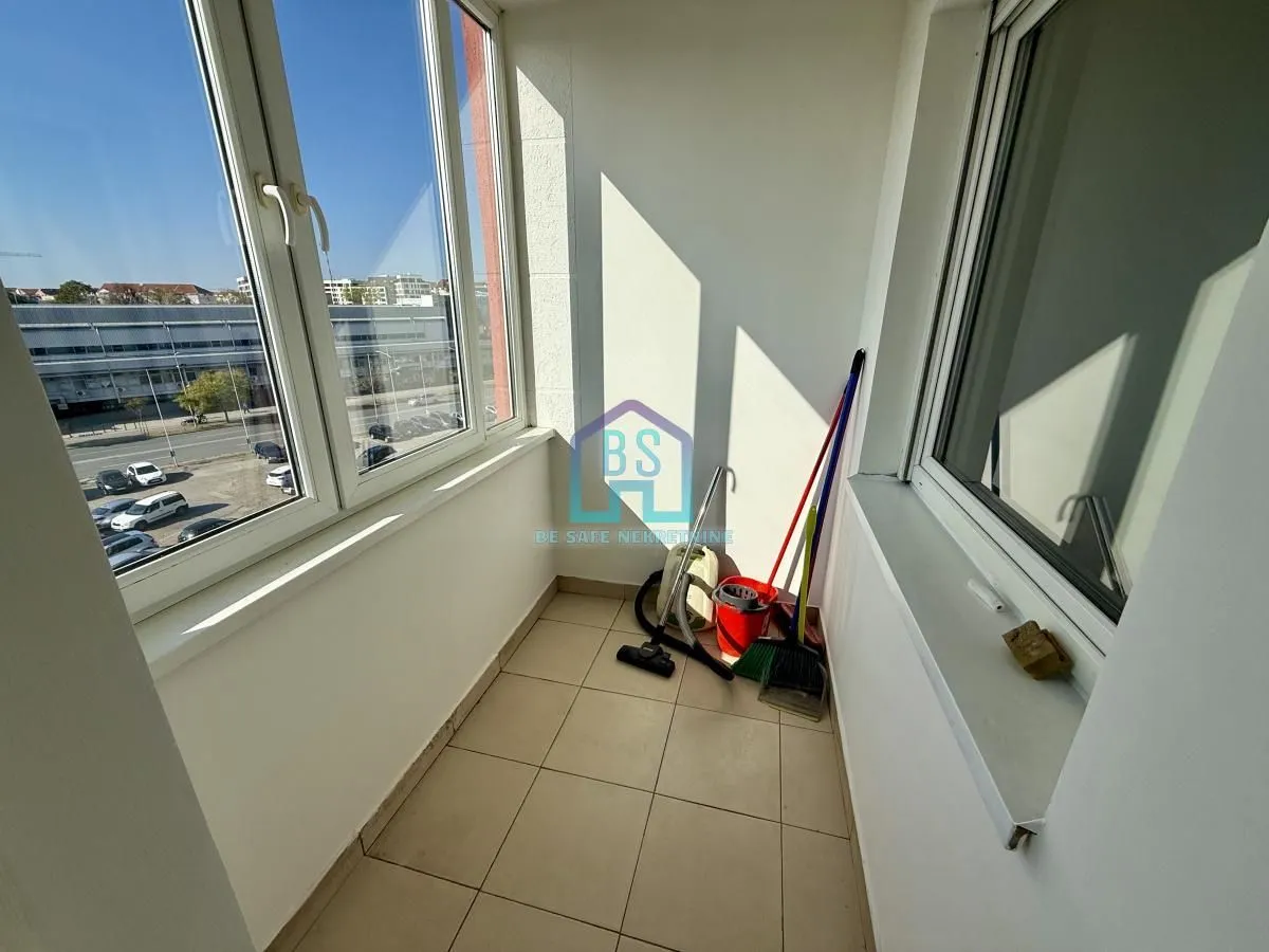 Zastakljeni balkon sa pločicama na podu i pogledom na ulicu.