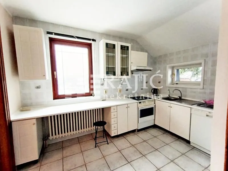 Spacious kitchen with white cabinetry and ceramic tiles.