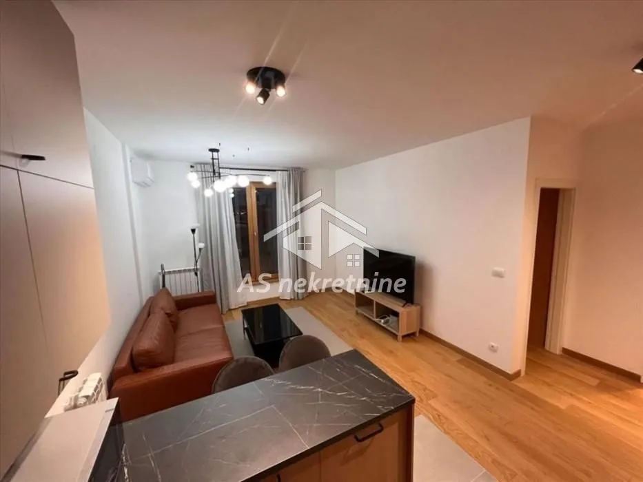 Living room with a sofa and television, connected to the kitchen.