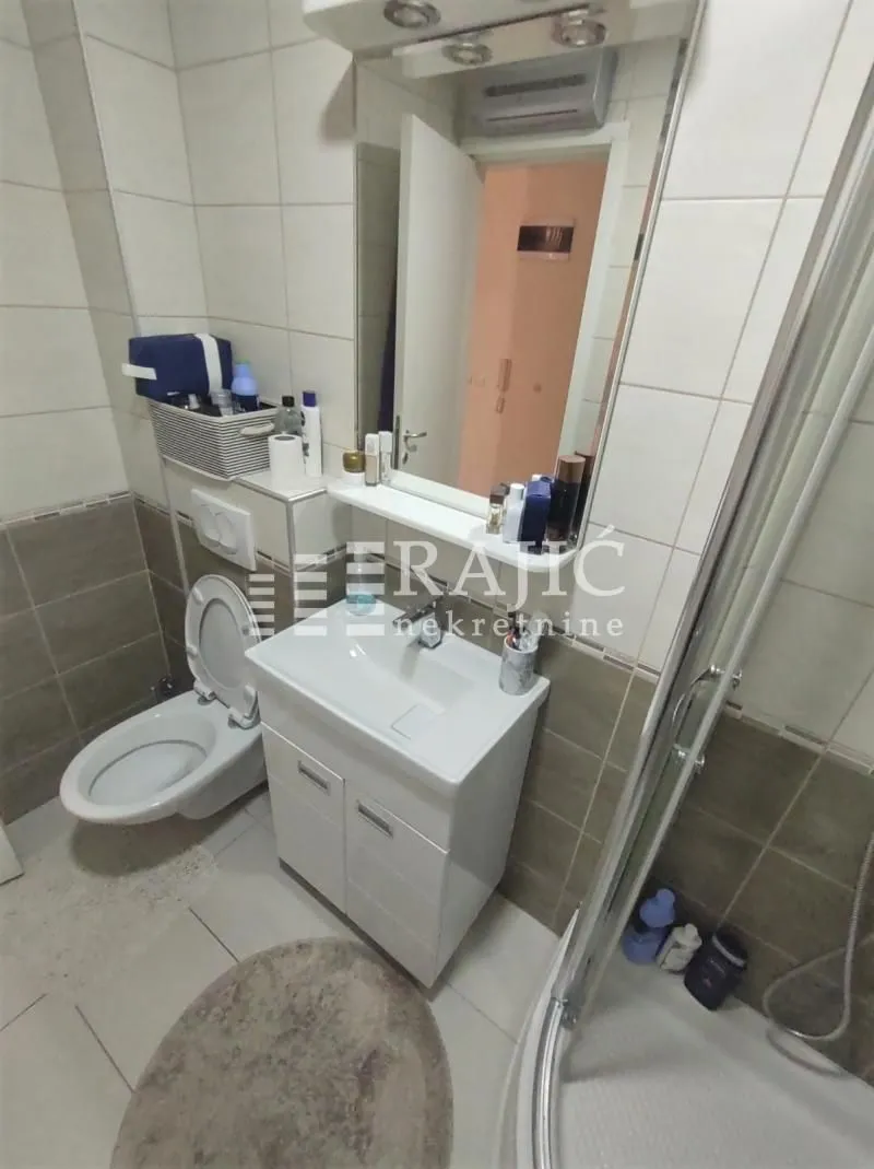 Smaller bathroom with a sink, toilet, and shower cabin.