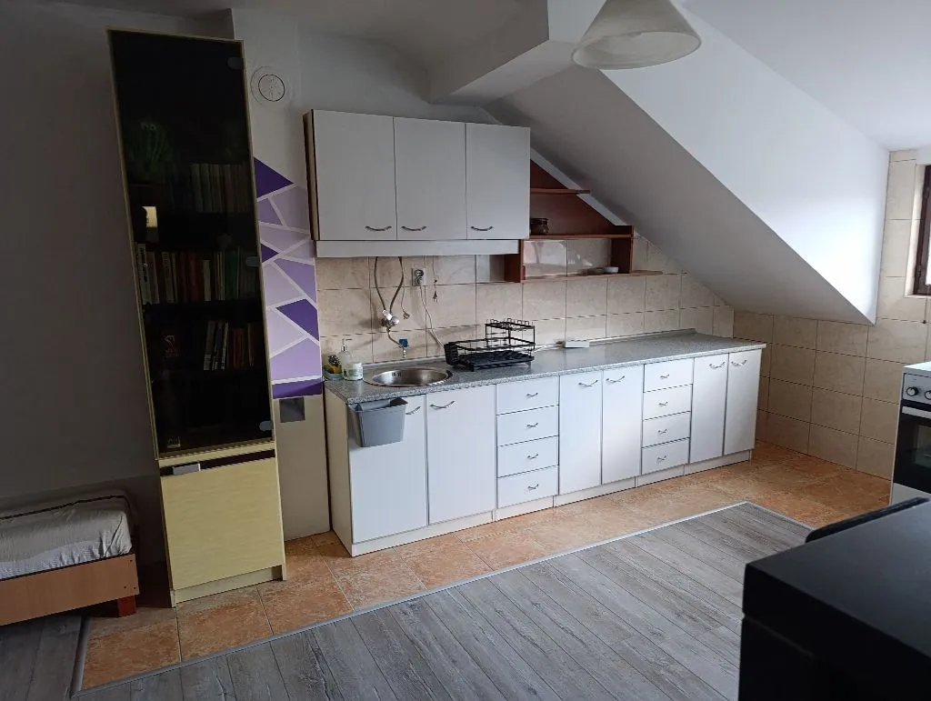 Attic kitchen with white cabinets and shelving.