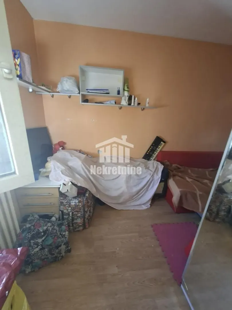 Manja soba sa krevetom i policama na zidu.