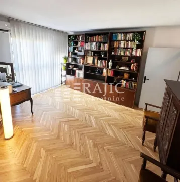 Spacious living room with wooden parquet flooring and a large bookcase. - image 3