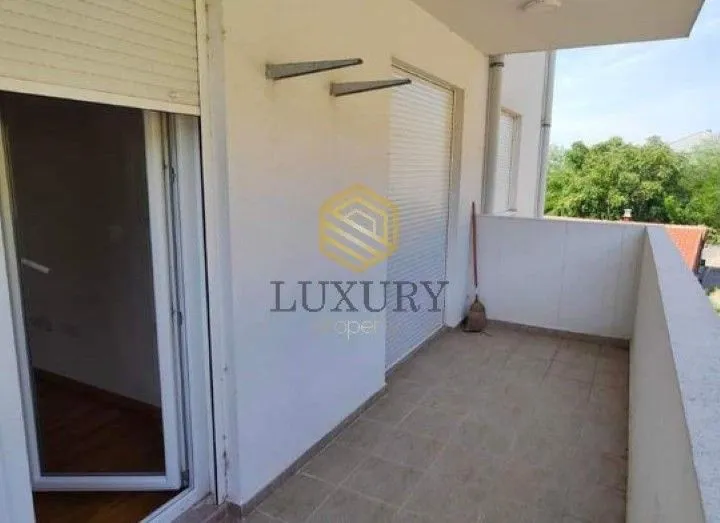 Covered balcony with tiled floor and window shutters.