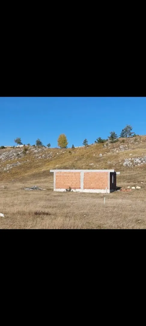 Nedovršeni objekat od cigle na placu u prirodi.